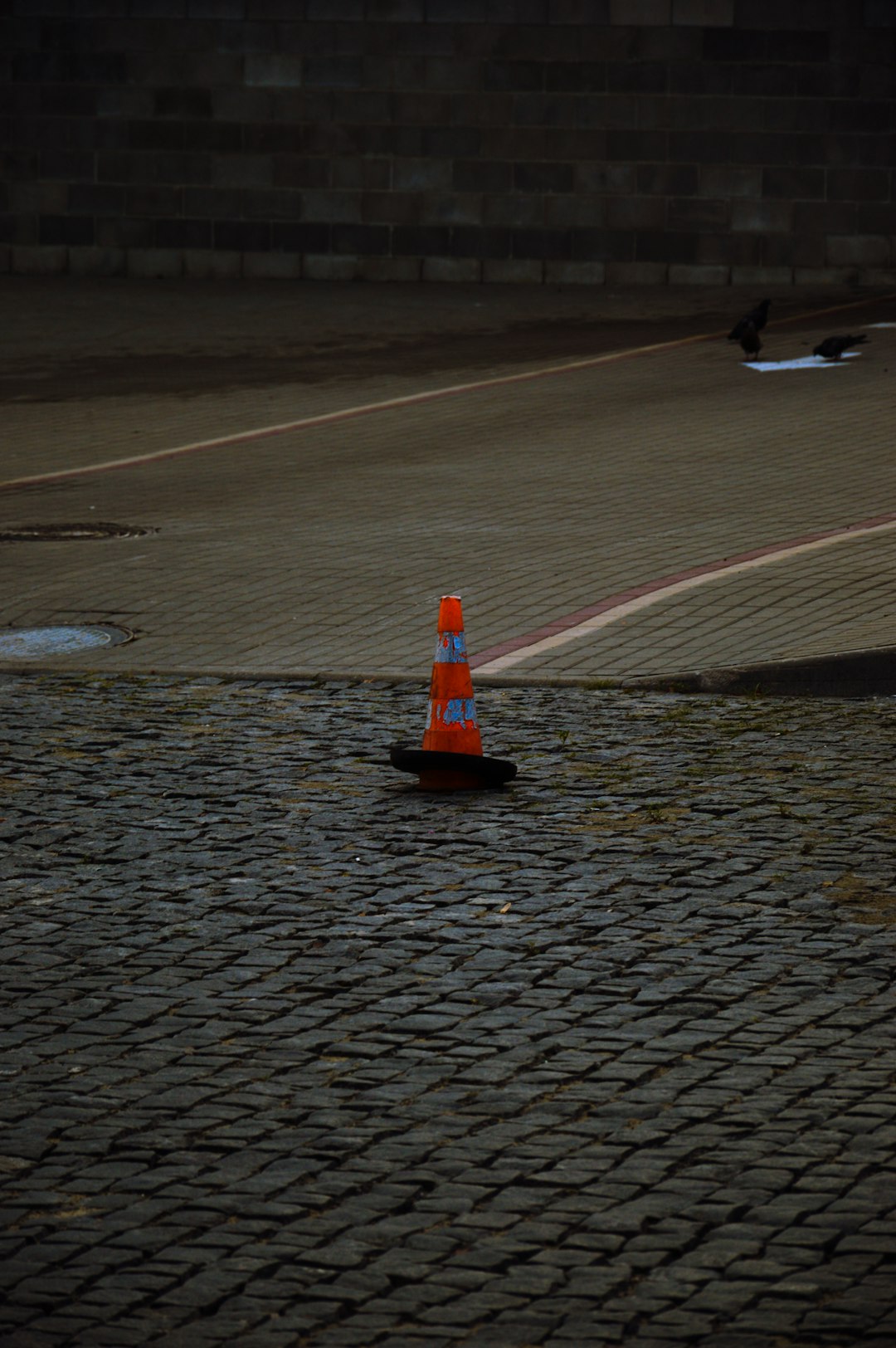 orange-traffic-cone-on-cobblestone-street-0y9im8frvtc